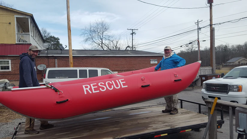 Two people carrying a Rescue raft